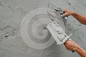 textured detail of plaster mortar while a worker plastering cement wall at construction site