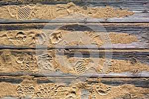 Textured detailed wooden flooring from planks on the sand on the beach with footprints of shoes