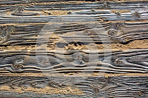 Textured detailed wooden flooring from planks on the sand on the beach with footprints of shoes.