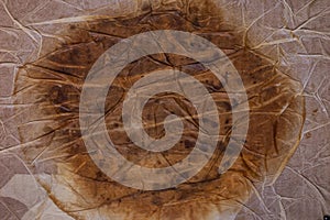 Textured dirty wrinkled brown old paper background with a large spot in the center. Horizontal background