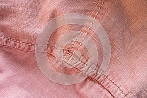 Textured fabric background in pink color with stitches. Place for text. Flatley. Close-up.