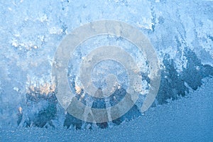 Textured frosty pattern on window lit by winter sun.