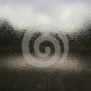 Textured glass surface with a rippled, wavy pattern, blurs the view of the background.