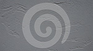 A textured gray plaster wall with subtle, irregular patterns and lines. The surface photo