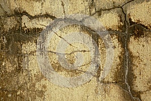 Textured grayish cracks on yellowish wall with brownish streaks