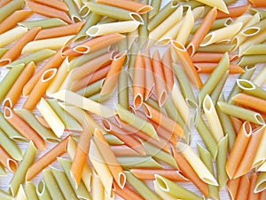 Textured Italian food background - colorful uncooked penne pasta on wooden table