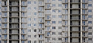 Textured pattern of a russian whitestone residential house building wall with many windows and balcony under constructio