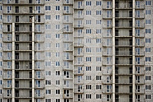 Textured pattern of a russian whitestone residential house building wall with many windows and balcony under constructio