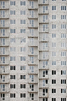 Textured pattern of a russian whitestone residential house building wall with many windows and balcony under construction