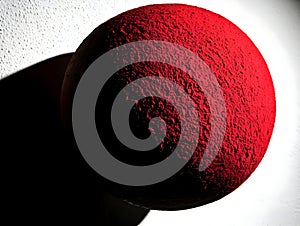 A textured red sphere casting a shadow against a light background