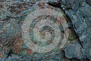 Textured rock fragment of different rocks with cracks and lichen