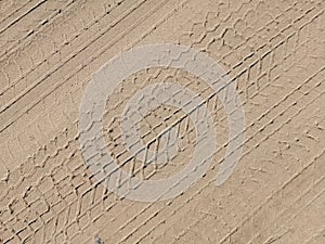 Textured sand road with diagonal tracks from a car tire tread