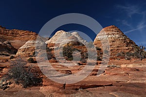 Textured sandstone red buttes under the blue sky.