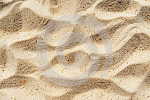 Textured sandy beach surface with ripples and granules of sand, close up. Nature pattern and texture concept. Background
