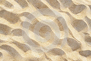 Textured sandy beach surface with ripples and granules of sand, close up. Nature pattern and texture concept. Background