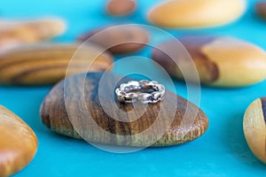 Textured silver ring on a wooden holder and blue background. Handcraft precious item.