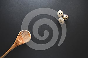 Textured spring background with small quail eggs and wooden spoon. Ecoproduct. Quail eggs on dark background photo