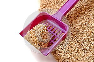 Textured wooden ecologic clumping yellow cat litter and a scoop with a clump.