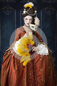 An 18th-Century woman wearing a robe a la Francaise and holding a fan and a mask. photo