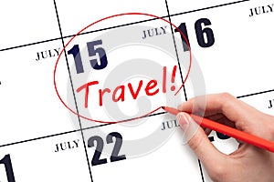 Hand drawing a red circle and writing the text TRAVEL on the calendar date 15July. Travel planning.