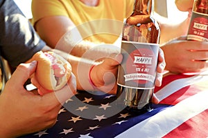 Holiday composition with multiple bottles of beer and hot dogs, American flag. Group of people celebrating Independence day of USA