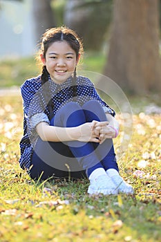 Thai 12s years girl sitting on garden field toothy smiling face