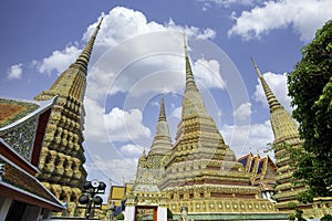 Thai ancient artistic architecture in Wat Poh with stupa complex and statue on sunny day and beautiful sky , Bangkok Thailand