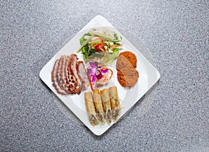 thai appetizer platter with grilled pork neck slice, siamese fish cake, thai spring roll and boneless chicken feet salad served in