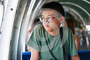 Thai Asian boy aged 10 to 12 years old, handsome and smart. Wearing a green t-shirt, glasses, he sat frowning, looking in a bad