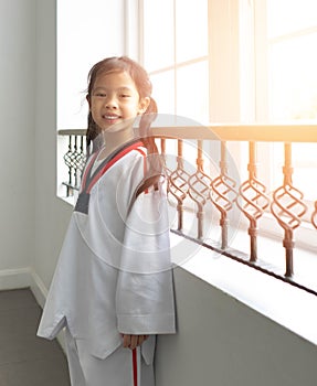 Thai asian girl kid standing relax beside windows after train taekwando in suit smile funny happy cute