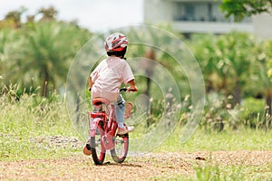 Thai Asian kid girl, aged 4 to 6 years old, looks cute, wears a helmet. and a bicycle She is play riding a bicycle to exercise in