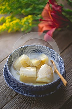 Thai banana in coconut milk with morning light on wooden background and copy space, Traditional conservative secret recipe