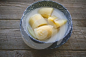 Thai banana in coconut milk with morning light on wooden background and copy space, Traditional conservative secret recipe