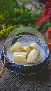 Thai banana in coconut milk with morning light on wooden background and copy space, Traditional conservative secret recipe