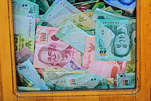 Thai banknotes money in the wooden donation box at the Buddhist