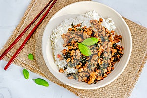 Thai Basil Chicken in a Bowl with Chopsticks, Garnished with Fresh Basil Leaves