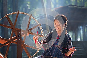 Thai Beautiful women smile in karen suit spinning thread on a ba