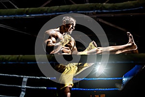 Thai boxer on boxing ring, kicking