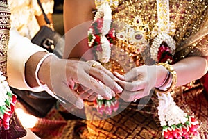 Thai bride and groom in Ceremony wearing a wedding ring of marriage celebration thai style at retro home in countryside of