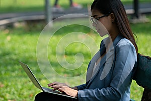 Thai Business Woman typing on Laptop keyboard to working in public park