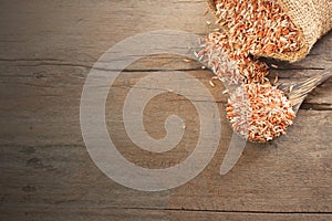 Thai cereal food - Top view of  red organic rice, brown rice in wooden spoon and sack lay on wooden table with copy space