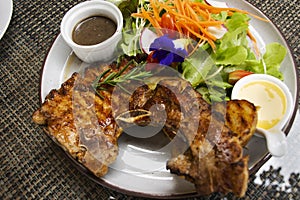 Thai chef cooking food fusion style cuisine roasted grilled fried Pork Chop Steak with spicy sauce and vegetables fruits salad on