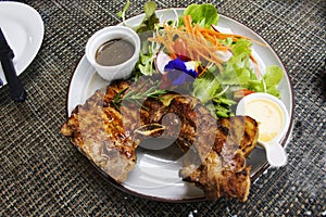 Thai chef cooking food fusion style cuisine roasted grilled fried Pork Chop Steak with spicy sauce and vegetables fruits salad on
