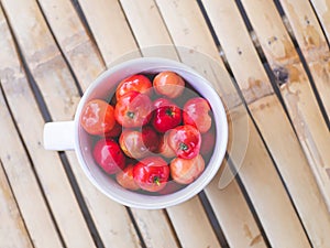 Red thai cherry in glass on bamboo wood pattern and background