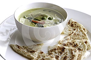 Thai chicken green curry in white bowl and paratha roti.