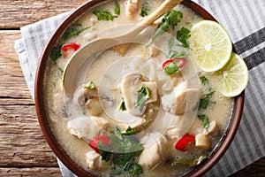 Thai chicken soup tom kha gai with coconut milk close-up in a bo