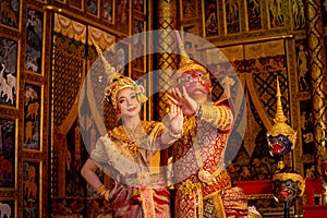 Thai classic masked man from the Ramakien character with red mask dance with beautiful Asian woman wear Thai traditional dress and