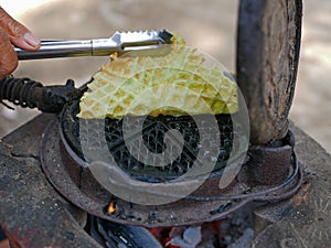 A Thai coconut waffle, so called ` Kanom Rung Peung ` or literally ` bee hive snack `, being cooked in its waffle iron photo