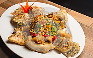 Thai cuisine Spicy and sour herb salad of fried Tilapia with baby tamarind leaves served on wood.