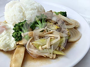 Thai cuisine. Stir-fried colorful vegetables, onion, broccoli, mushroom with meat in white plate with rice and fried egg on white